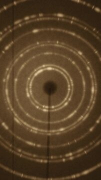 X-ray powder diffraction Debye rings rotating crystal grain texture dark detector seamless loop in subtle brown tones vertical 9:16