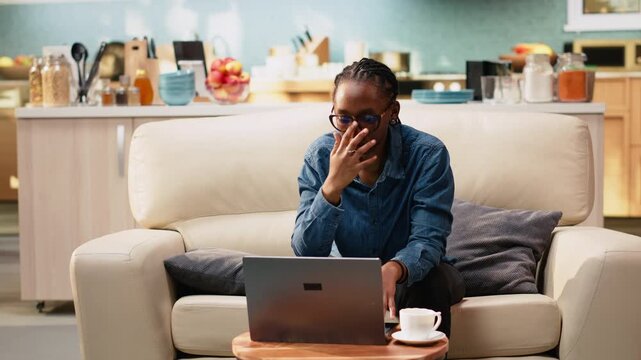 Young woman stretching muscles and relaxing at coffee table, remote work on laptop causes neck discomfort and stiffness due to incorrect posture. Takes break for work-life balance.