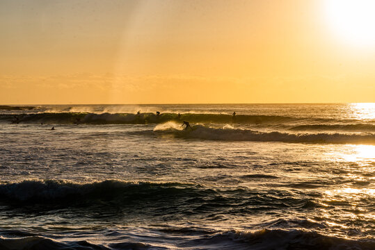 Bright Sun Glare Over Ocean and Beach with Distant Surfers