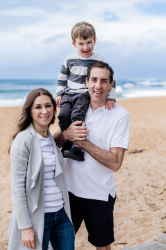 Family having fun at the beach: dad with laughing son and smiling mum
