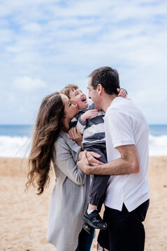 A joyful family shares laughter and love outdoors at the beach by the ocean