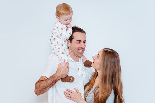 playful parents and their son sharing a parenthood moment on a white background