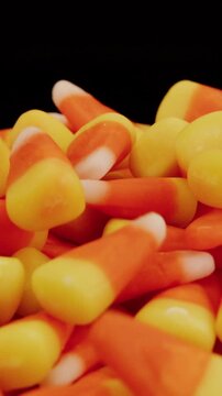 Candy corn falling on pile in slow motion on spinning turntable vertical video