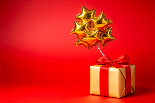 Golden Gift Box with Star Balloons on Red Background