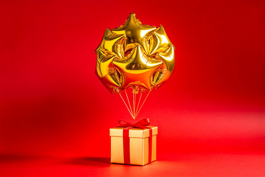 Golden Star Balloons Attached to Gift Box on Red Background
