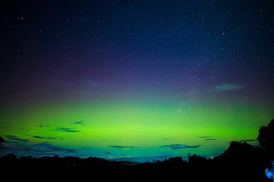 glowing green and blue aurora over dark landscape