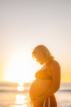 Expecting mother at Manly Beach during sunrise, in a moment of joy and love