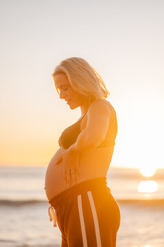 pregnant woman at Manly Beach during sunrise showing baby bump