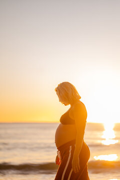 pregnant women walking alongside Manly Beach during sunrise with serene ocean backdrop