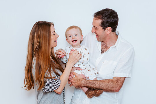 family of three playing together in white background (young boy, mother and father)