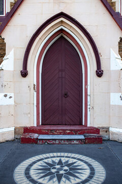 Gothic arched wooden doorway of historic church building with decorative stone pavement star pattern