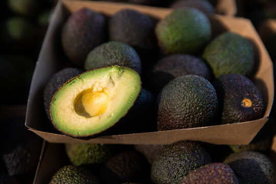 avocados in trays at the markets with half an avocado on the top