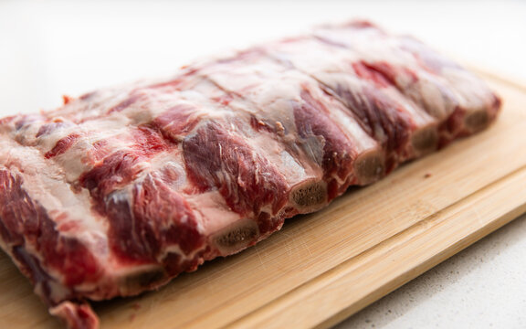 beef ribs sitting on a chopping board in natural light