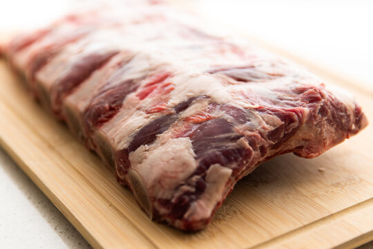 rack of raw beef ribs on a chopping board