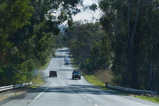 Red car going uphill with cars and caravan going downhill