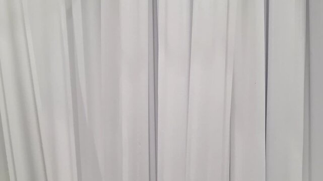 Row of white polystyrene moldings or baseboards stacked vertically in a hardware store. Construction materials, home renovation, interior design.