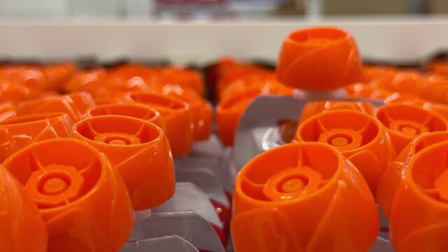 Close-up view of bright orange plastic caps on children food fruit puree pouches on a store shelf. Baby nutrition, plastic packaging, child merchandise, retail supermarket display.