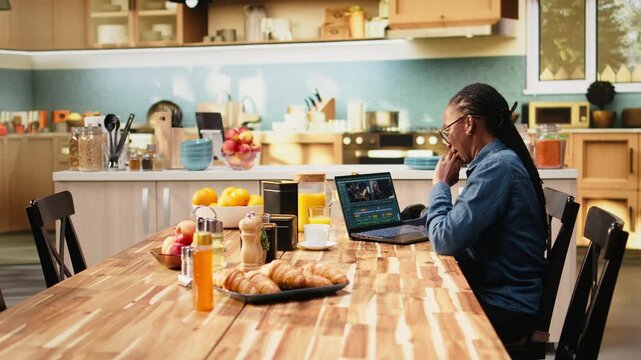 Woman video editor stretches muscles after assembling montage on laptop, with timeline editing, video production, cramps and muscle stiffness at table.