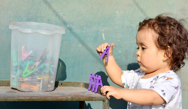 Toddler playing with clothespins.
