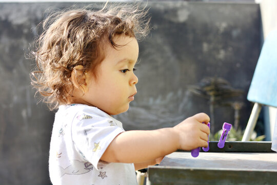 Toddler playing with clothespins.