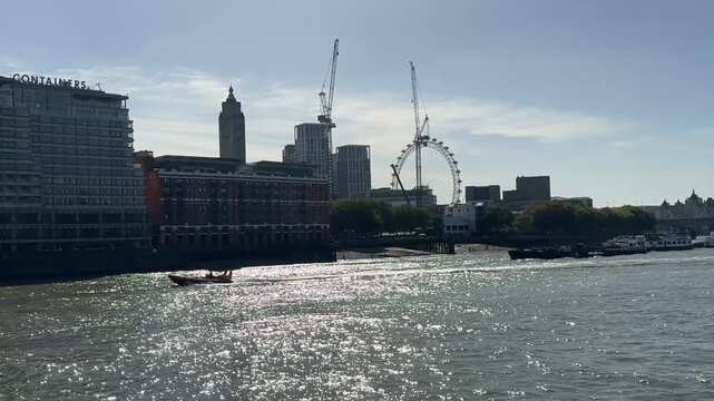 4K view looking west along the River Thames toward the London Eye, with the South Bank skyline and sunlight reflecting across the water.