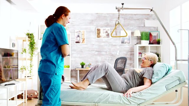 Nurse helping senior woman get into bed and settle under blanket
