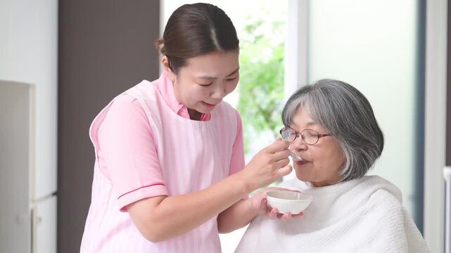 訪問介護で高齢者の食事介助をするホームヘルパー、在宅介護、食事支援、食べることをサポートする女性介護職のイメージの動画