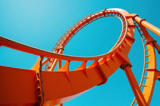 Bright orange rollercoaster track curves against clear blue sky. Steel loop structure rises high in summer daylight. Amusement park ride architecture shows modern design, engineering. Empty track