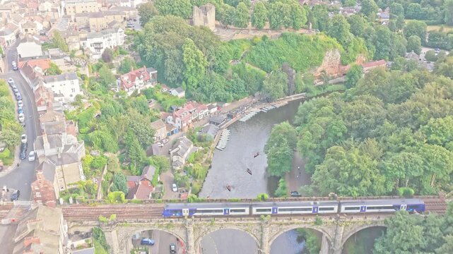 Northern passenger train crosses Knaresborough Viaduct on the Harrogate Line above the River Nidd, beside woodland and the historic town in Knaresborough, North Yorkshire, England, United Kingdom, aer