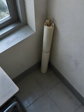 Rolled paper chart standing in the corner of a tuition room curled around a slim wooden dowel