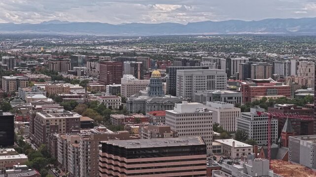 Denver downtown skyline with the gold dome of the colorado state capitol building and distant mountains suny day drone video 4K