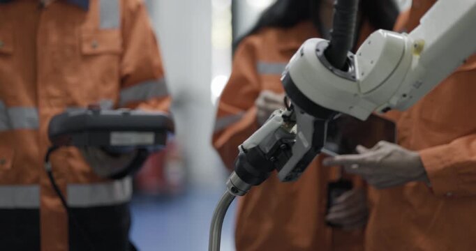 Female and Male engineers checking or maintenance electronic in AI or artificial intelligence robot arm in the manufacturing automation and robotics manufacture room. Service technical engineer.