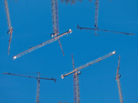 Abstract composition of construction cranes against clear blue sky