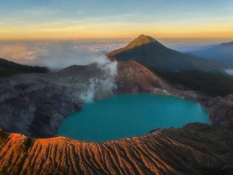 Majestic mount ijen volcano crater with turquoise sulfur lake illuminating under sunlight.