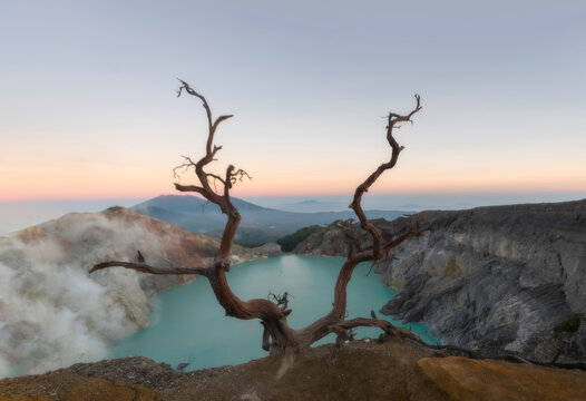 Majestic mount ijen volcano crater with turquoise sulfur lake illuminating under sunlight.