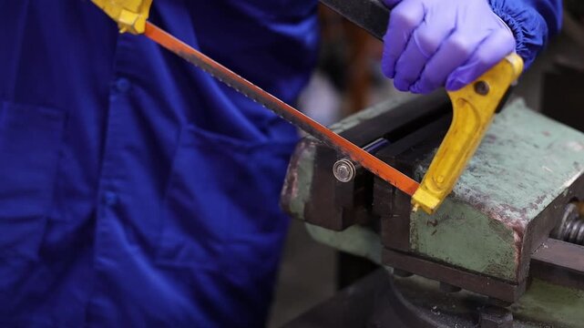 Technician wearing protective gloves uses a hacksaw to open a used 18650 lithium-ion battery clamped in a vise, showing a battery disassembly process for recycling, inspection, and material recovery