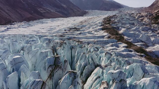 Deep Blue Ice Crevasses, Seracs, And A Dark Medial Moraine Line Running Through A Massive Flowing Glacier In Greenland. - aerial shot