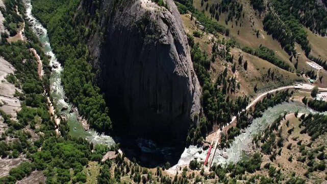 Aerial view of the iconic Shen Zhong Mountain rock formation in Keketuohai Scenic Area, Xinjiang, with turquoise river winding through forested valley