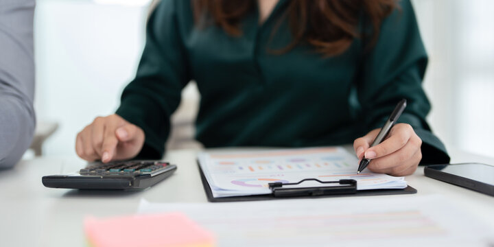 Woman holding pen pointing on paper using calculator for business financial accounting calculate money bank loan rent payments manage expenses finances taxes doing paperwork concept, close up view.