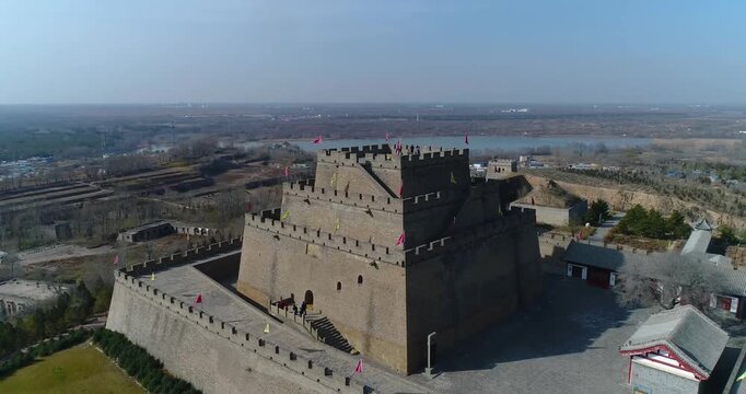 Changcheng Town North Tower in Yulin, aerial drone view of ancient Ming Dynasty fortress with crenellated walls, red flags, and surrounding flatlands