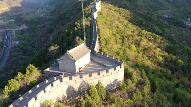 Great Wall of China at Juyongguan Pass winding through forested mountains, aerial drone footage at golden hour