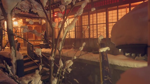 枝に積もる雪と格子窓から漏れる旅館の温かい明かりの冬景色スローモーション