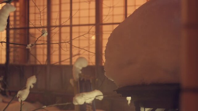 枝に積もる雪と格子窓から漏れる旅館の温かい明かりの冬景色スローモーション