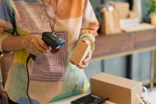 Mature Asian woman using barcode reader scan handcrafted jewelry package