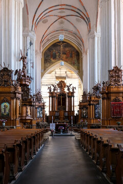 Vilnius, Lithuania &ndash; The stunning historic interior of the Bernardine Church, showing intricate wooden altars, Gothic arches, and religious artwork inside the nave.