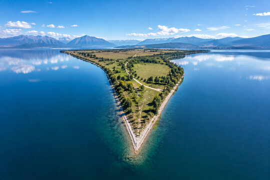 Aerial view of a sharp triangular peninsula jutting into a calm, reflective lake, geometric landscape.