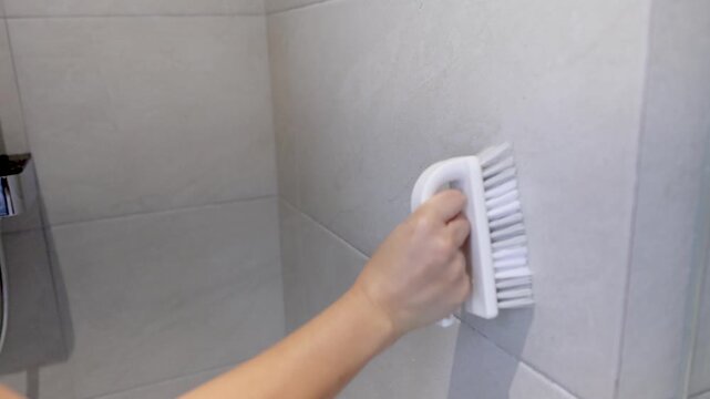 Woman Hand Scrubbing Bathroom Wall Tiles with Cleaning Brush