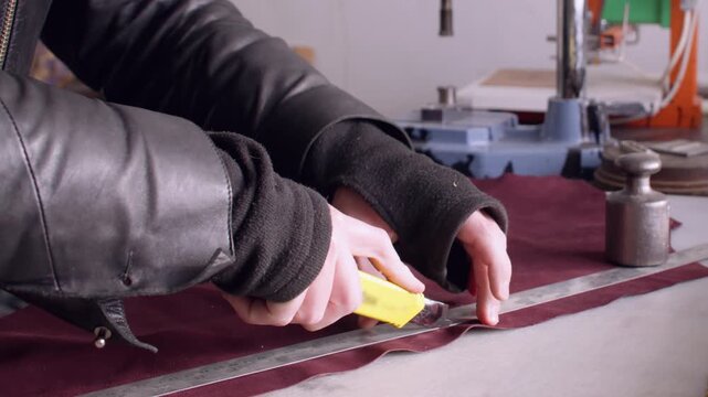 Craftsman factory. Handmade footwear. Master man hands using stationery knife ruler sewing machine cutting material at shoes store.