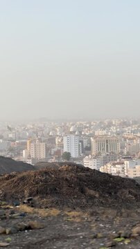 Hazy panoramic view of Medina cityscape and surrounding hills from a rocky viewpoint.