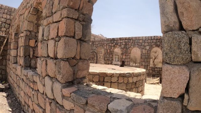 Panning out of ancient stone ruins with a covered well to a dry desert landscape.